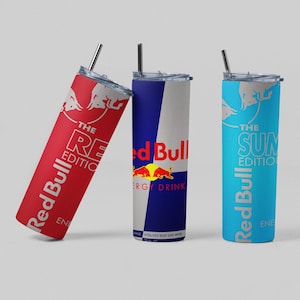 May include: Three Red Bull-branded stainless steel tumblers with straws. One is red with "The RE Edition" text, another is blue and white with the Red Bull logo, and the third is light blue with "The SUN Edition" text.
