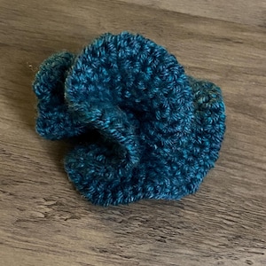 May include: A teal blue crocheted flower with a textured surface.