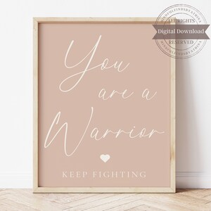Pode incluir: Um download digital imprimível de uma citação motivacional em fonte cursiva branca sobre um fundo rosa claro. A citação diz "You are a warrior. Keep fighting." com um pequeno símbolo de coração branco entre as palavras "warrior" e "keep".