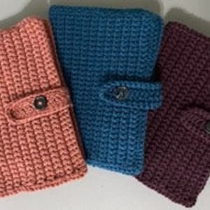 May include: Three crocheted zippered pouches in pink, blue, and purple. Each pouch has a button closure and a strap.