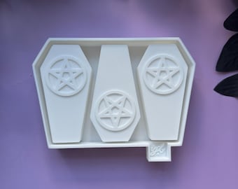 May include: White silicone mold with three coffin-shaped cavities, each featuring a pentagram design. The mold is labeled "ygl."
