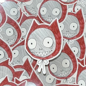 May include: A collection of red and white stickers featuring a cartoon character with a mischievous grin, large eyes, and a red hooded cloak. The character has a white bow tied around its neck.