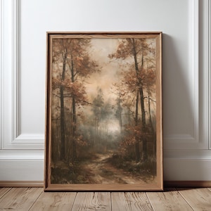 May include: A rectangular wall art print in a light brown wooden frame featuring a forest landscape painting. The artwork displays tall trees with autumn-toned foliage in shades of brown, orange, and muted green, with a path leading into the misty woods.