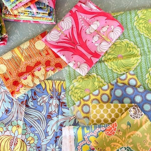 May include: A collection of folded fabric pieces featuring various floral and botanical patterns in vibrant colours including pink, orange, lime green, blue, and yellow. The textiles display intricate, repeating designs with visible selvedge edges.