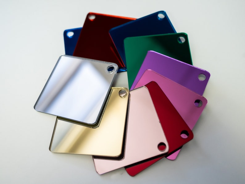 May include: A set of ten square mirror tiles in various colors, including silver, gold, red, pink, purple, green, blue, and red. Each tile has a small hole in the corner.