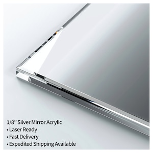 May include: A close-up of a 1/8 inch thick silver mirror acrylic sheet. The sheet is smooth and reflective. The text "1/8" Silver Mirror Acrylic" is visible in the image. The text "Laser Ready", "Fast Delivery", and "Expedited Shipping Available" is also visible in the image.