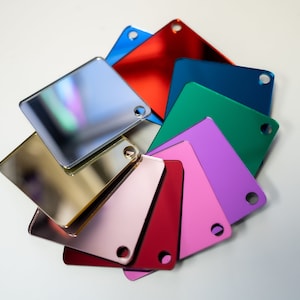 May include: A set of nine square mirror tiles in various colors, including gold, silver, red, pink, green, blue, and purple. The tiles are arranged in a circular pattern.