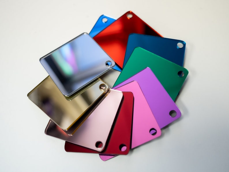 May include: A set of nine square mirror tiles in various colors, including gold, silver, red, pink, green, blue, and purple. The tiles are arranged in a circular pattern.