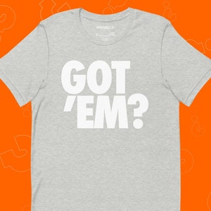May include: A grey t-shirt with the text "GOT 'EM?" printed in white.