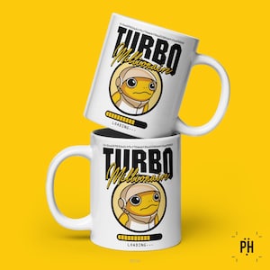 Puede incluir: Taza de cerámica blanca con un personaje de dibujos animados amarillo que lleva un casco y una barra de progreso que dice "CARGANDO..." La taza tiene texto negro que dice "TURBO MILLIONAIRE".