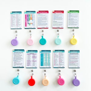 May include: A collection of medical reference cards with various topics, including atrial fibrillation and COVID treatment, displayed on a white wall. Each card is paired with a retractable badge reel in a different color, such as purple, pink, and teal.