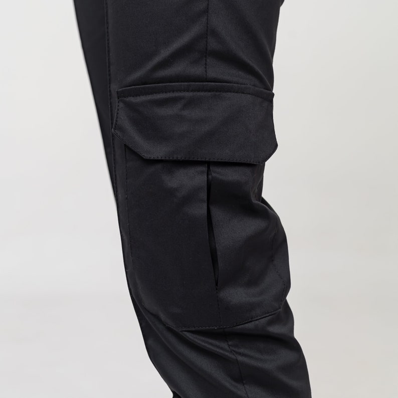 May include: Black cargo pants with a large cargo pocket on the right leg.