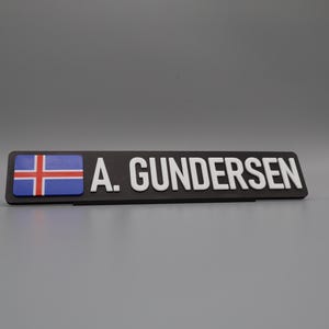 A single sign on a stand for display purposes, in with a grey background. The sign has the flag of norway on the left side, followed by the text "A. GUNDERSEN".