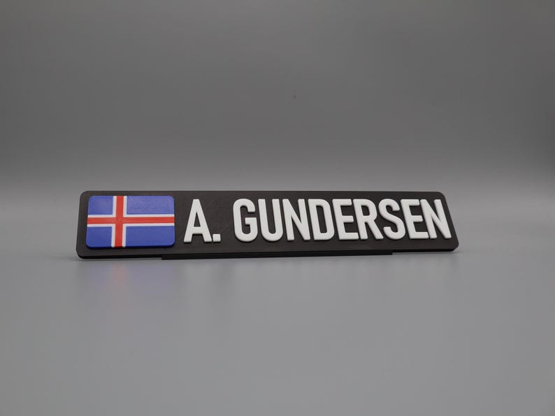 A single sign on a stand for display purposes, in with a grey background. The sign has the flag of norway on the left side, followed by the text "A. GUNDERSEN".