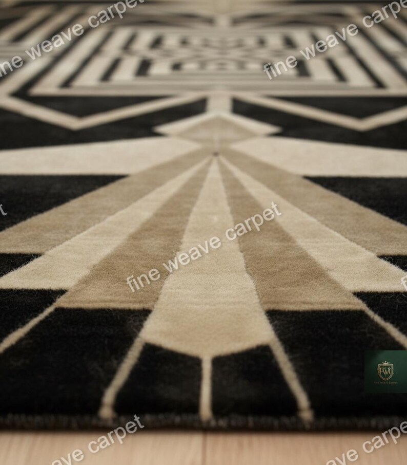 Pu&ograve; includere: Tappeto a motivi geometrici in nero, beige e marrone chiaro. Il tappeto presenta un motivo Art D&eacute;co ripetuto con linee radiali e forme angolari. La trama del tappeto &egrave; visibile, suggerendo un materiale morbido e tessuto. Le parole "fine weave carpet" sono stampate sul tappeto.