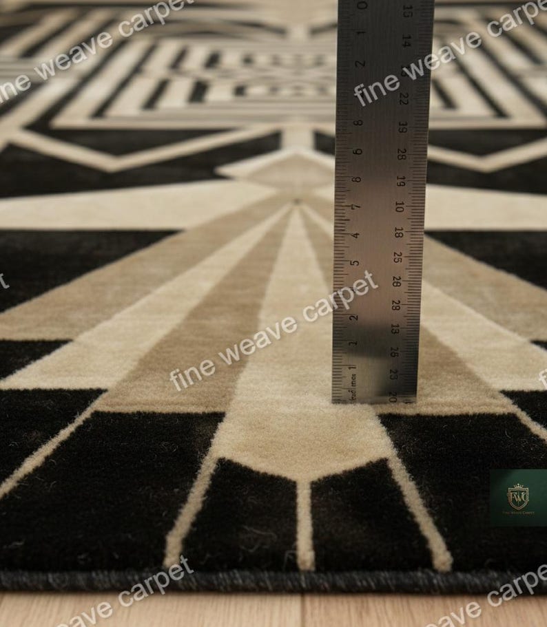 Pu&ograve; includere: Tappeto con motivo geometrico in nero, beige e grigio. Il tappeto presenta un design simmetrico con linee radiali e forme geometriche. Il testo "fine weave carpet" &egrave; visibile. Un righello &egrave; posto sul tappeto.