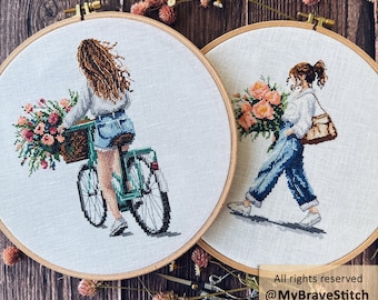 May include: Two circular wooden embroidery hoops containing cross-stitch art on light fabric. One shows a person on a bicycle with a flower basket, the other a person walking with flowers. Text reads: All rights reserved @MyBraveStitch Hanna Levchuk.