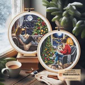 Op de afbeelding: Twee ronde kruissteekringen met kerstscènes. Eén toont een persoon die leest bij een raam met een kerstboom, de andere toont een persoon die aan het kruissteken is. De ringen zitten in houten frames. Een kopje koffie en kaneelstokjes staan op de voorgrond.