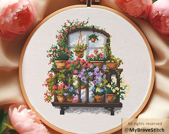 Puede incluir: Bordado de punto de cruz de un balcón con flores de colores en macetas. El diseño presenta un marco de madera, una ventana con vistas y una variedad de flores en tonos rojos, rosas, morados y amarillos. El bordado está en un bastidor de madera.