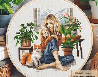 May include: A cross-stitch embroidery in a round wooden hoop depicting a person with long blonde hair sitting on the floor next to a ginger and white cat, surrounded by potted plants and a window. Text reads: All rights reserved @MyBraveStitch Hanna Levchuk.