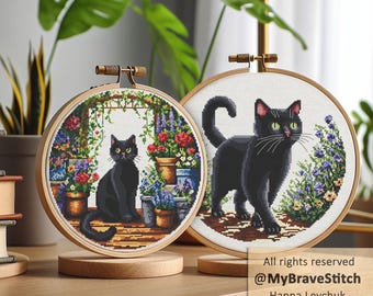 May include: Two circular wooden embroidery hoops containing cross-stitch patterns of black cats. The left hoop shows a cat sitting near potted flowers and a trellis. The right hoop features a black cat walking among garden plants. Text reads All rights reserved @MyBraveStitch Hanna Levchuk.