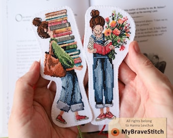 以下が含まれることがあります： 2つのクロスステッチのブックマーク。1つは本を運ぶ人、もう1つは花を読んでいます。どちらの人物もデニムのオーバーオールと赤い靴を履いています。ブックマークは開いた本の前で保持されています。タグには「MyBraveStitch」と書かれています。