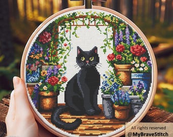 May include: Cross-stitch embroidery in a wooden hoop featuring a black cat sitting in a garden scene. The design includes colorful flowers in pots, a wooden archway, and the text "All rights reserved @MyBraveStitch Hanna Levchuk."