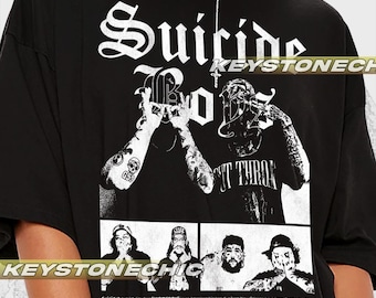 Puede incluir: Camiseta gráfica en blanco y negro con el texto "Suicide Boys" en una fuente gótica. La camiseta también presenta una imagen en blanco y negro de un hombre con tatuajes y el texto "G59 Cut Throat".