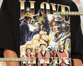 Puede incluir: Camiseta negra con un estampado gráfico de un grupo de personas con cascos y sosteniendo pepitas de oro. El texto "I LOVE MINERS" está impreso en letras doradas en la camiseta.