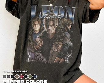 Puede incluir: Una camiseta de manga corta en color gris carbón con un estampado gráfico de estilo vintage de Leon Kennedy de Resident Evil. El diseño incluye varios retratos del personaje, el texto "LEON" y "Kennedy" y detalles de rayos.
