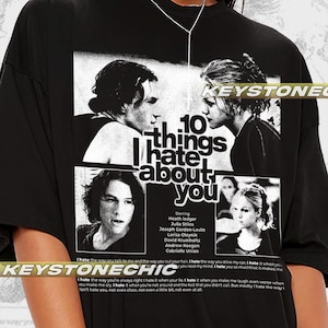 以下が含まれることがあります： 「10 Things I Hate About You」の映画ポスターがプリントされた白黒のグラフィックTシャツ。ポスターには映画のタイトル、俳優の名前、映画のシーンが掲載されています。