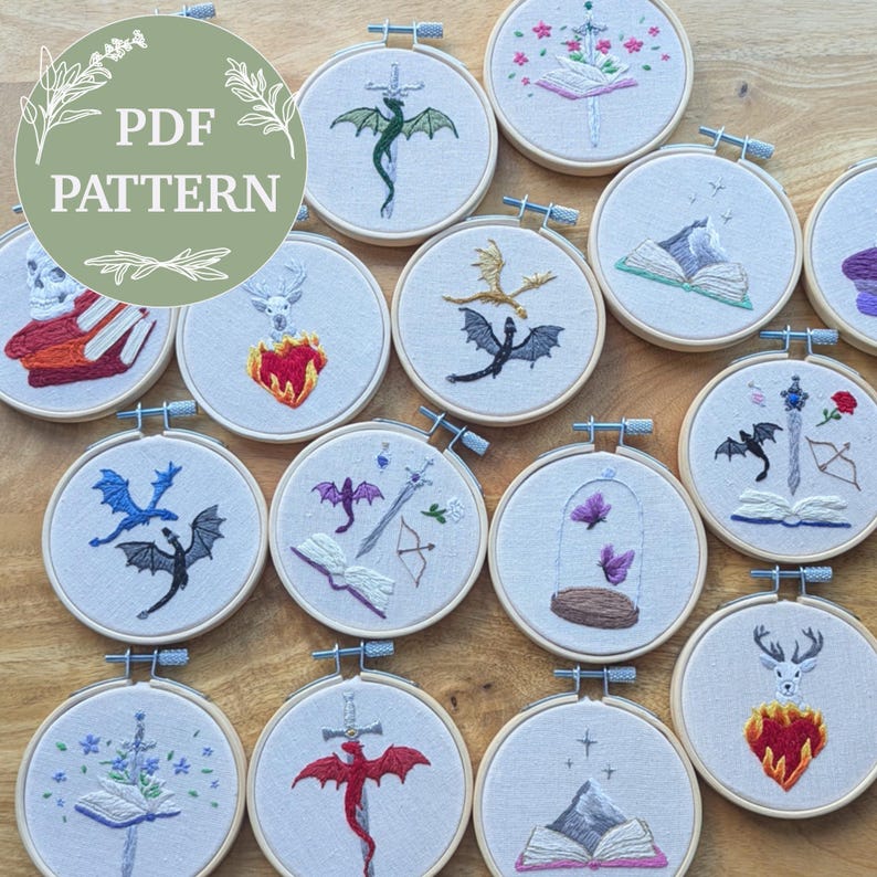 May include: A collection of embroidered hoops featuring fantasy-themed designs. Dragons, swords, books, and floral elements are stitched in various colors on a cream-colored fabric. The text "PDF PATTERN" is displayed on a green circle.