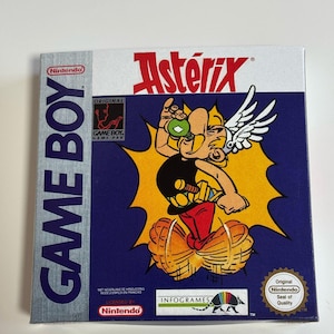 May include: A Game Boy cartridge for the game Asterix, featuring a cartoon image of Asterix on the front. The cartridge is in its original packaging, which is blue and yellow with the Nintendo logo.