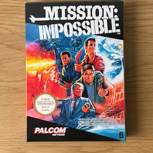 Puede incluir: Una caja en blanco y negro para el videojuego Mission: Impossible para Nintendo Entertainment System. La caja presenta una tarjeta de título con el nombre del juego en letras blancas sobre un fondo negro. La caja también presenta una imagen de los personajes del juego, incluido Tom Cruise, y un sello de calidad de Nintendo.