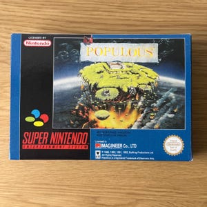 Puede incluir: Una caja de cartucho de juego Super Nintendo Entertainment System azul para el juego Populous. La caja presenta una imagen colorida de una isla flotante con un paisaje verde y un cielo azul. El texto "Populous" está impreso en blanco sobre un fondo azul. La caja también incluye el texto "Licensed to Imagineer Co., LTD" y el sello de calidad de Nintendo.