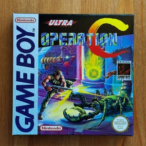 Puede incluir: Caja de juego de Nintendo Game Boy para "Operation C". La ilustración muestra a un soldado disparando a una criatura gigante con forma de escorpión. El título del juego está en letras grandes y coloridas, con los logotipos de Nintendo y Game Boy.
