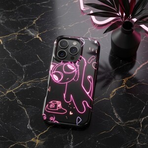 May include: A black smartphone case featuring a neon pink line art illustration of a stylized cat-like creature. The design includes a small box-shaped object and abstract shapes, all rendered in glowing pink outlines against a solid black background.