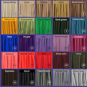 Peut inclure: Un nuancier de couleurs présentant 25 nuances de cordons différentes, chacune avec un nom et un numéro. Les couleurs vont des tons neutres comme le crème et le gris aux teintes vives comme le jaune, le bleu et le rouge. Les cordons sont disposés en rangées et en colonnes.