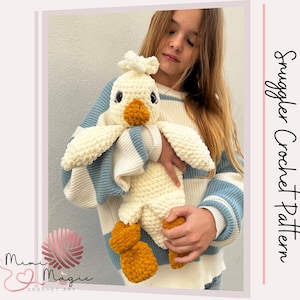 May include: A white crocheted plush toy shaped like a duck with orange feet. The duck is being held by a person wearing a blue and white striped sweater.