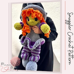 May include: A handmade crochet witch doll featuring bright orange yarn hair, a green face, and large dark eyes. The doll wears a grey hat, a grey and purple dress with a ruffled skirt, and striped purple and grey legs. Text reads Snuggler Crochet Pattern.