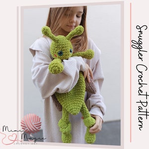 Peut inclure: Un jouet en peluche crocheté vert en forme de limace avec de grands yeux. Le jouet est tenu par une personne portant un pull crème. Le texte "Smuggler Crochet Pattern" est visible sur le côté droit de l'image.