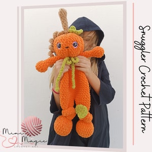 Peut inclure: Un jouet en peluche en forme de citrouille crocheté avec une tige et des feuilles vertes. Le jouet est orange et a un visage amical avec des yeux violets. Le jouet est tenu par une personne portant une veste noire.