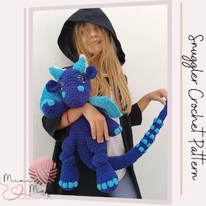 May include: A blue and turquoise crocheted dragon toy with a white and blue wing. The dragon is being held by a person wearing a black hooded jacket.