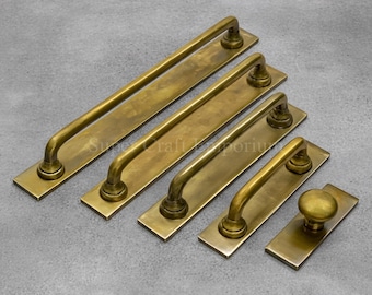 May include: A collection of antique brass door pulls and knobs in various sizes. The hardware features a warm, aged finish and a classic, curved handle design. The set includes long bar pulls and a round knob.