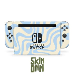 Puede incluir: Una consola Nintendo Switch con un patrón ondulado en azul claro y crema. La consola tiene botones negros y una pantalla negra. El texto "NINTENDO SWITCH" se muestra debajo de la pantalla. El logotipo "SKIN ONN" está en la parte inferior.