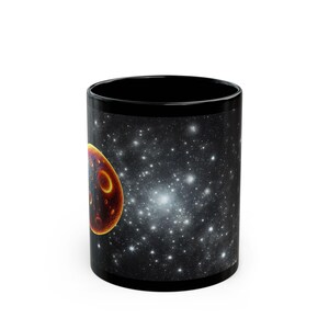 May include: Black ceramic mug with a galaxy print featuring a red and orange planet. The mug has a white star in the center of the galaxy.