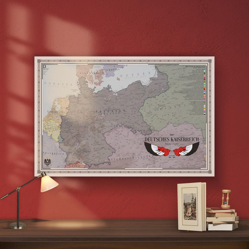 May include: A rectangular wall map titled DEUTSCHES KAISERREICH featuring a muted color palette of gray, beige, and light blue. The map displays historical borders, geographical labels, a list of flags on the right, and a central eagle wing graphic.
