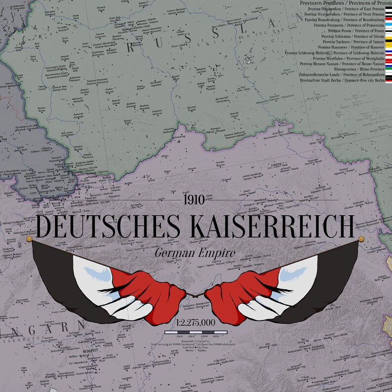 May include: A historical map of the 1910 German Empire, titled DEUTSCHES KAISERREICH, featuring a grey background with black text, a scale of 1:2,275,000, and a central graphic of two stylised wings coloured in black, white, and red stripes.