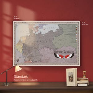 May include: A rectangular wall map titled Deutsches Kaiserreich featuring historical German territories in muted tones of grey, tan, and green. The map measures 91.44 cm by 60.96 cm and includes a central eagle wing graphic and text labels.