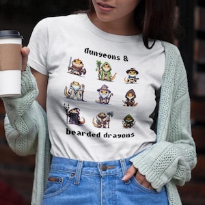 May include: White t-shirt with a graphic of bearded dragons dressed as Dungeons & Dragons characters. The text "Dungeons & Bearded Dragons" is printed below the graphic.